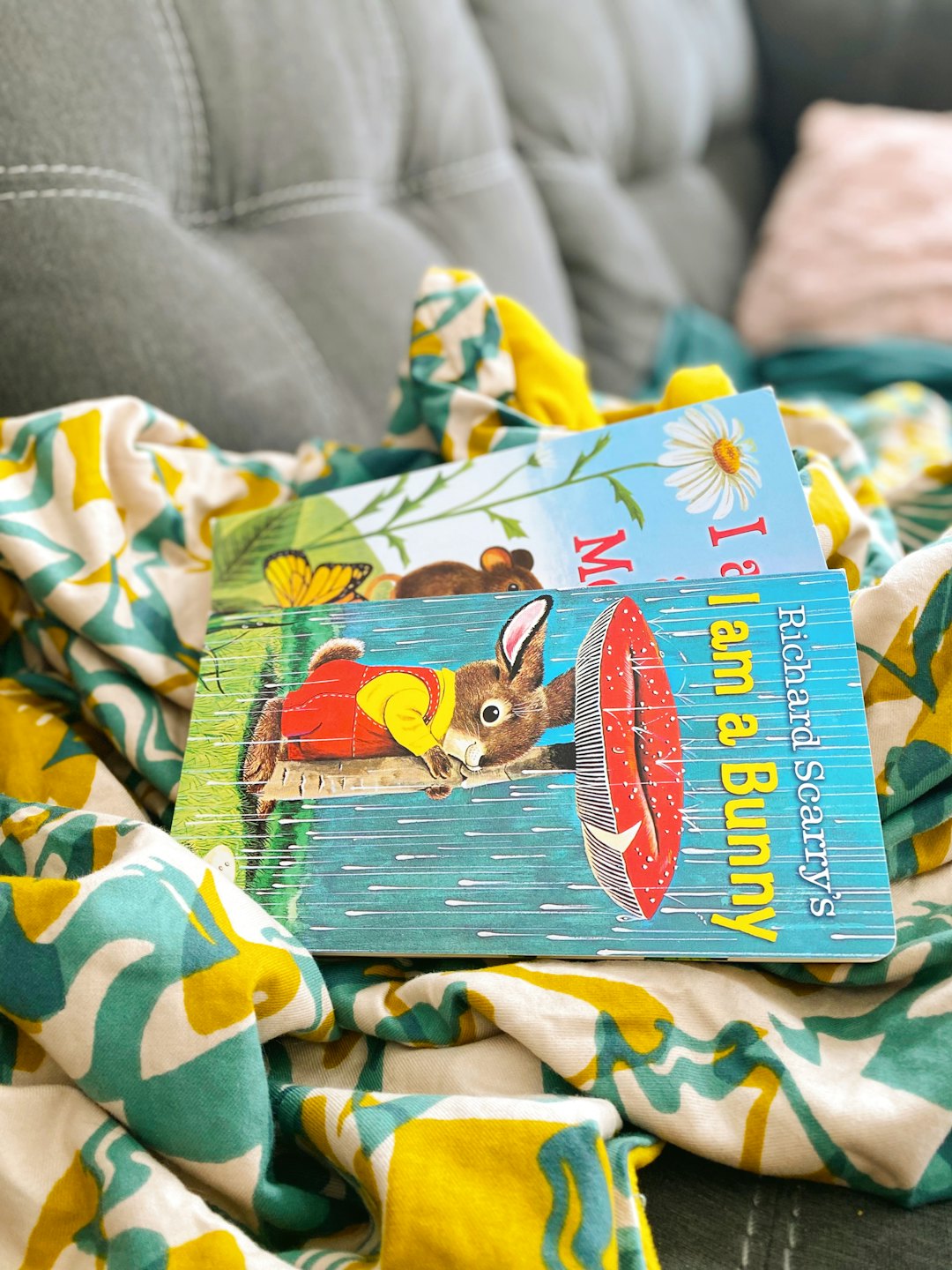 Two children's books rest on a patterned blanket.