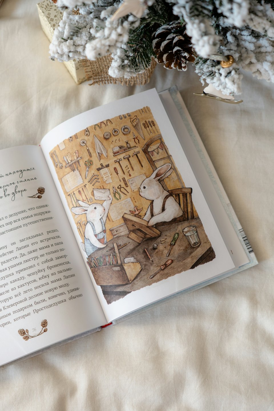 An open children's book sits on fabric beside holiday decorations.