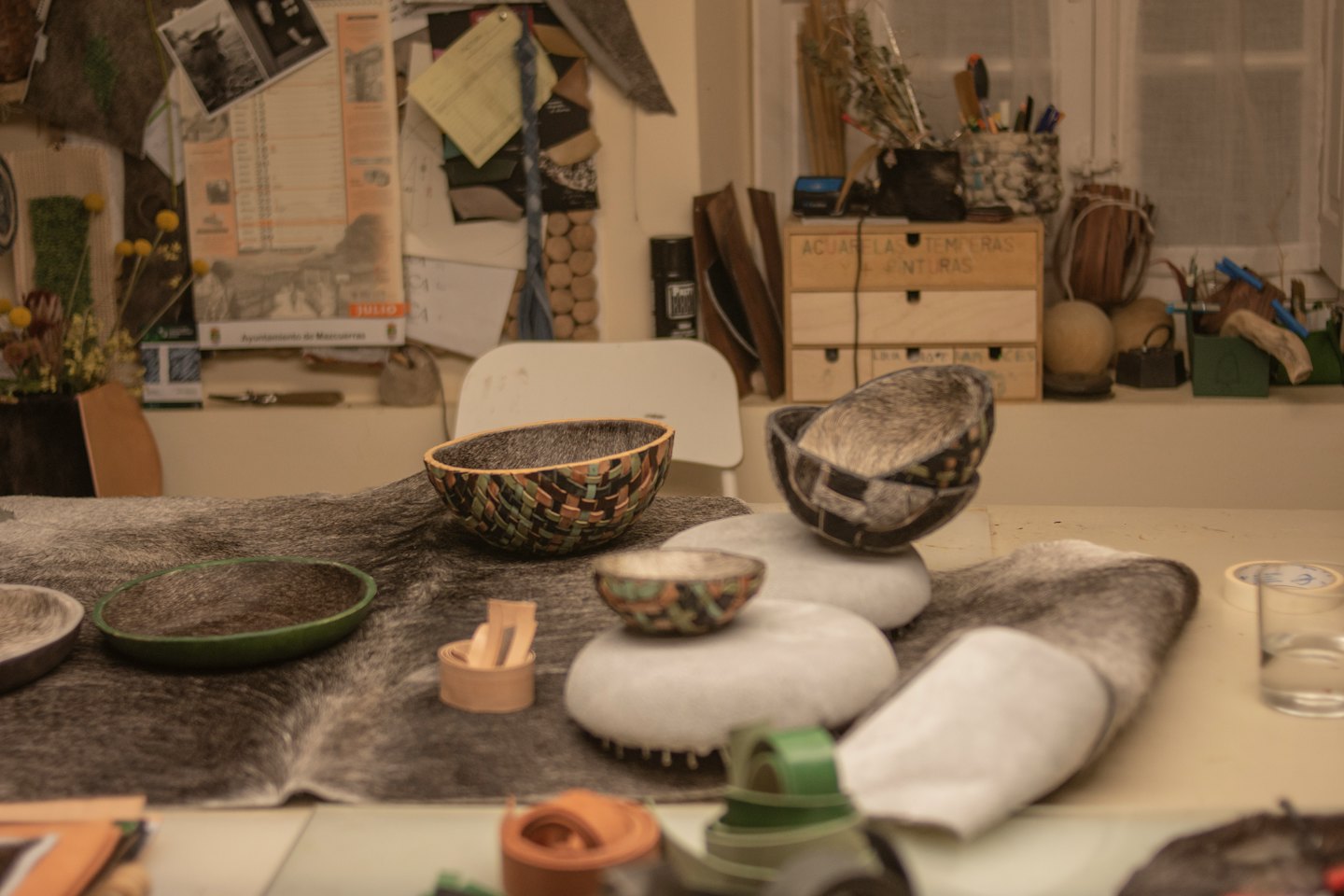 Handmade bowls displayed on animal hide at a crafting table.