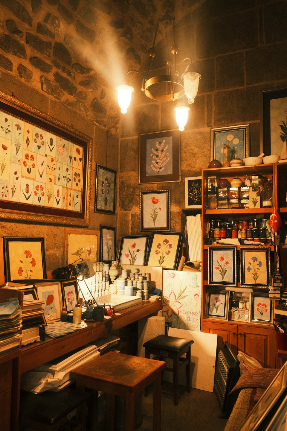 Framed floral artworks displayed in a rustic stone art studio.